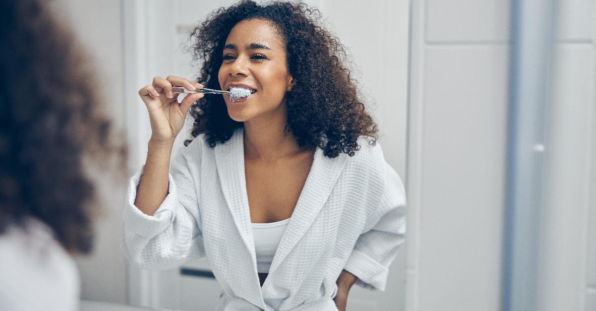 curly-headed pretty lady brushing her teeth