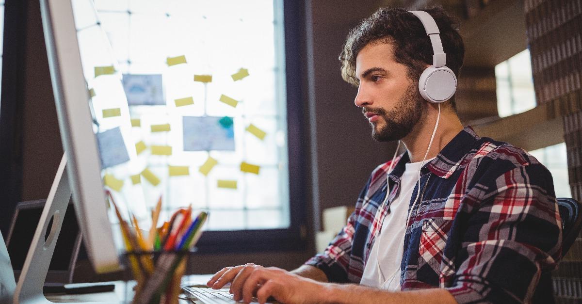 creative businessman using computer while listening to music