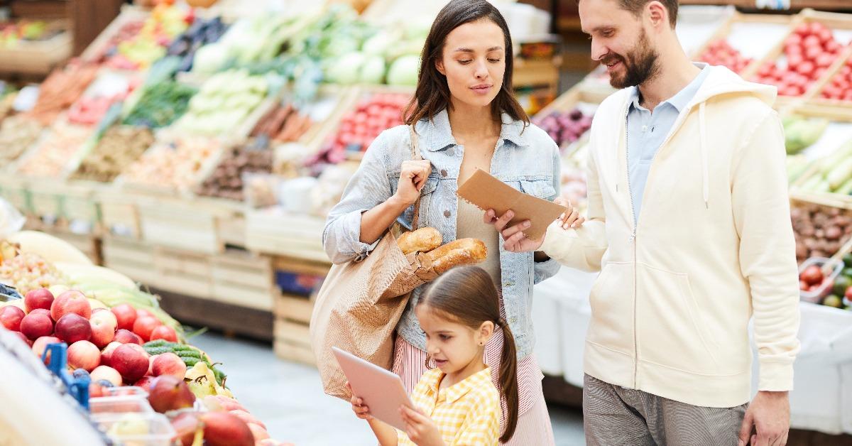 family in casual clothing buying fresh organic food in farmers market