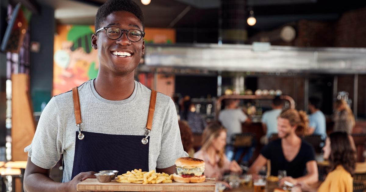waiter serving food to customers in busy bar restaurant