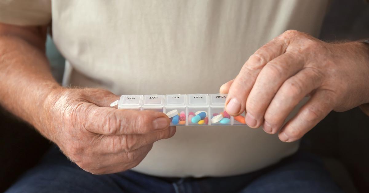 senior man holding container with pills