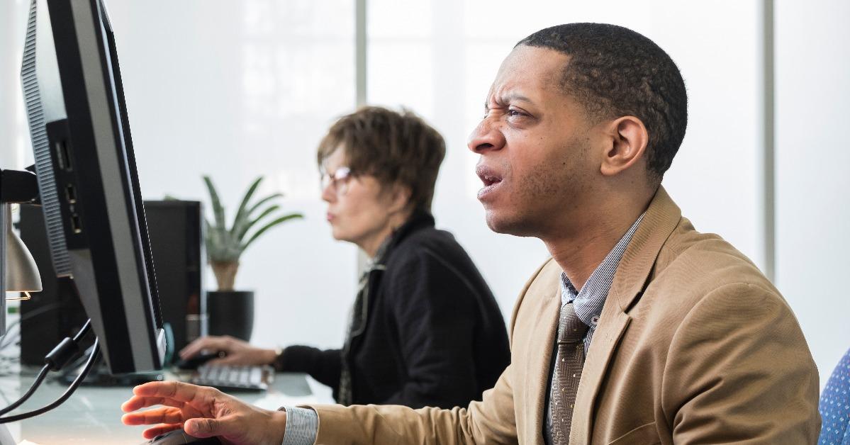man working on computer looking frustated