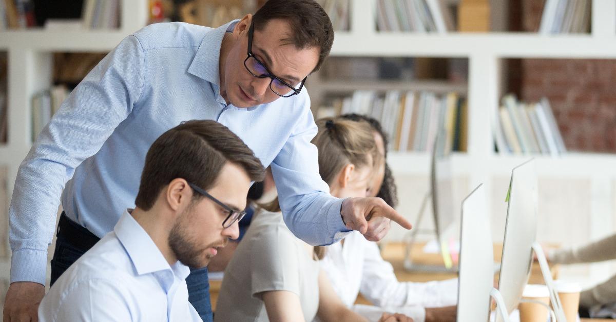 angry boss criticizing male employee for computer mistake