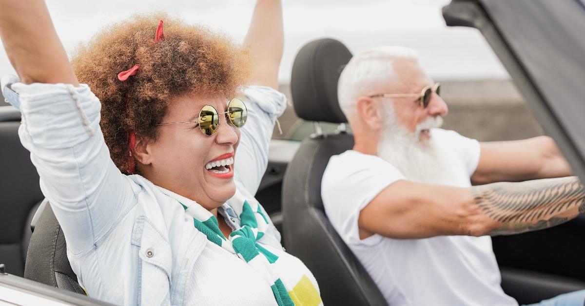 senior multiracial couple having fun with convertible car 