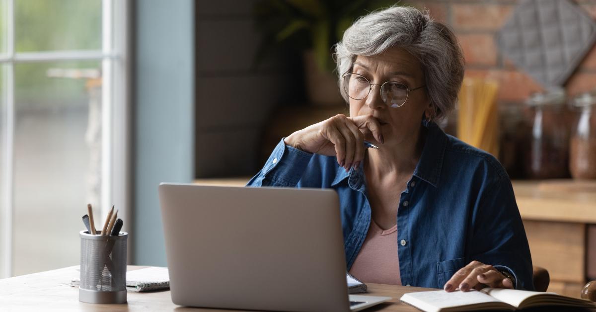 mature woman wearing glasses working on laptop online