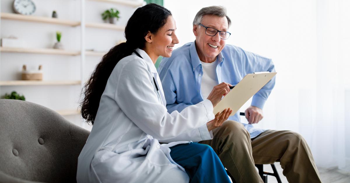 doctor asking senior impaired male patient in wheelchair to sign insurance policy