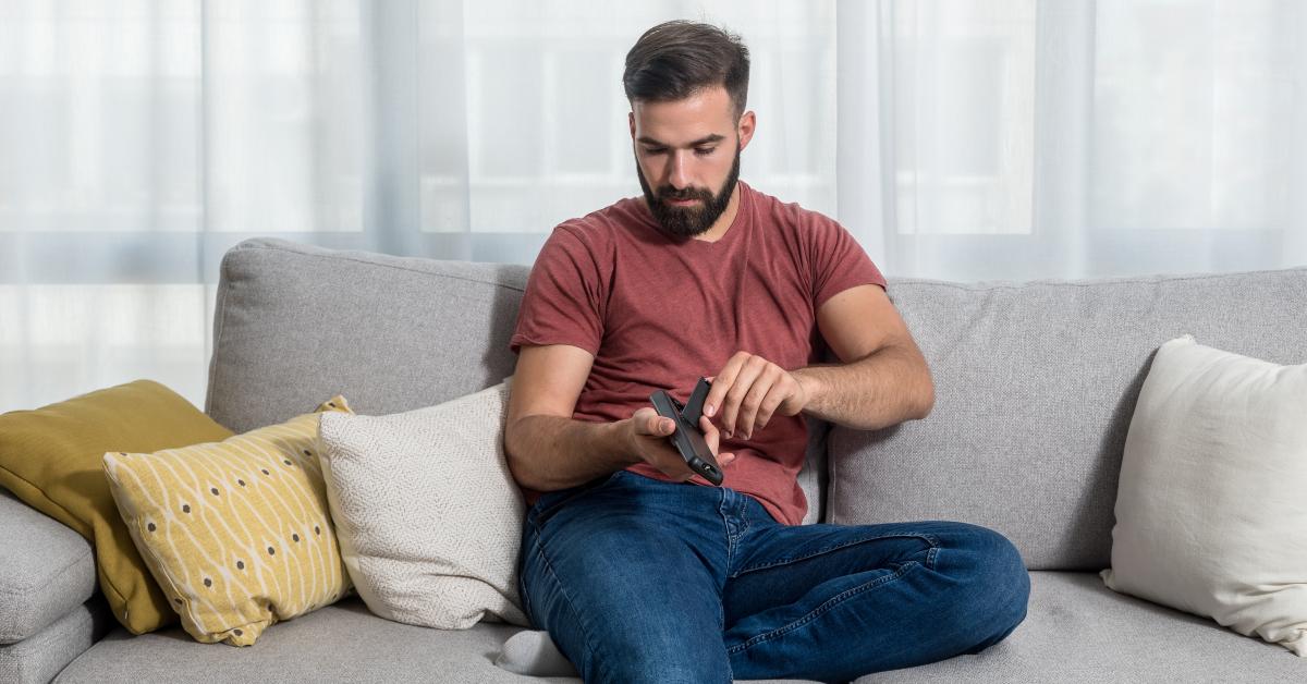 man opening the tv remote control to change the dead batteries