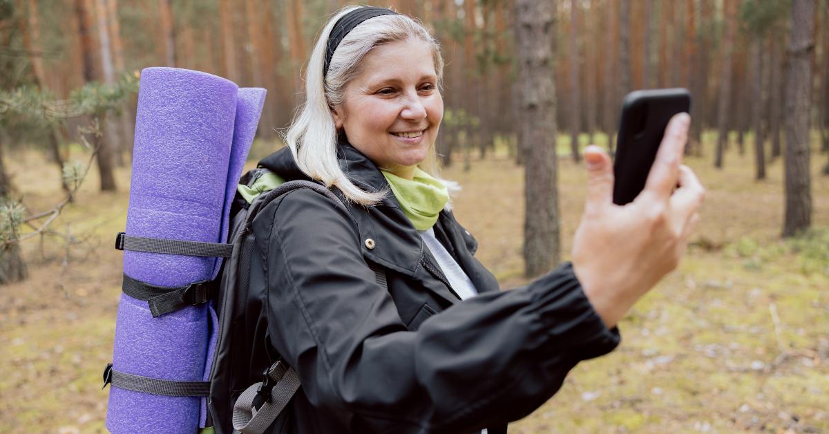 woman in the woods holding smartphone in hand