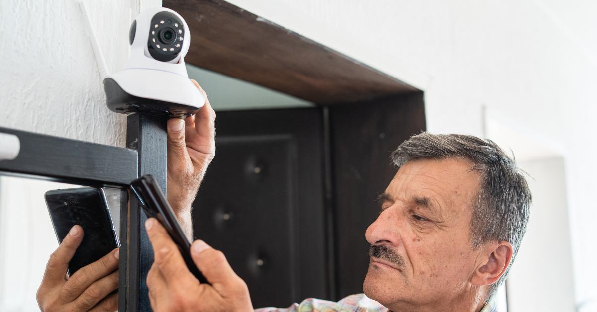 senior man holding home security surveillance camera