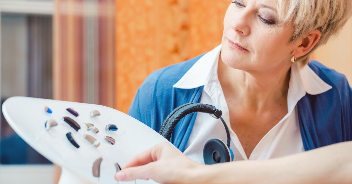 senior woman with impairment choosing hearing aid in shop
