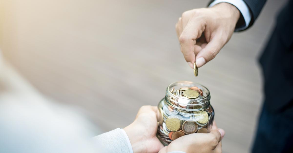 hand putting coin in the glass jar