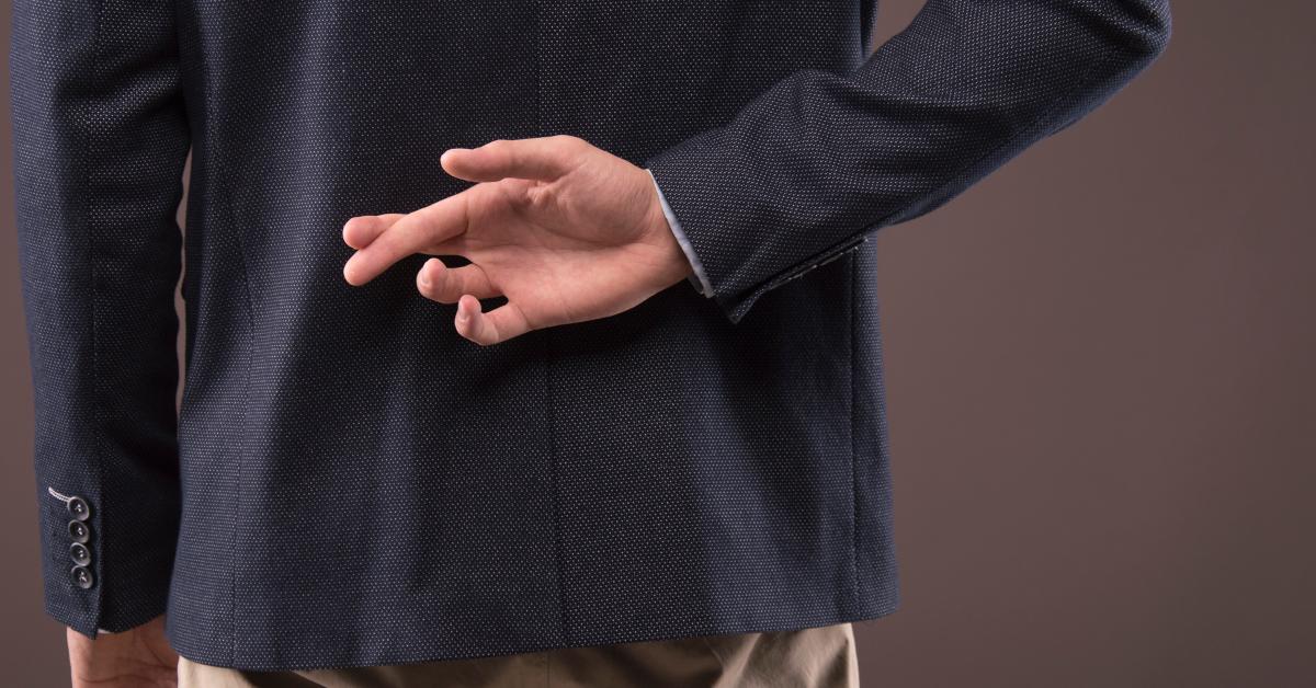 man in a suit crossed his fingers behind his back