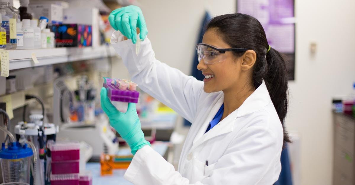 young scientist in lab coat wearing nitrile gloves