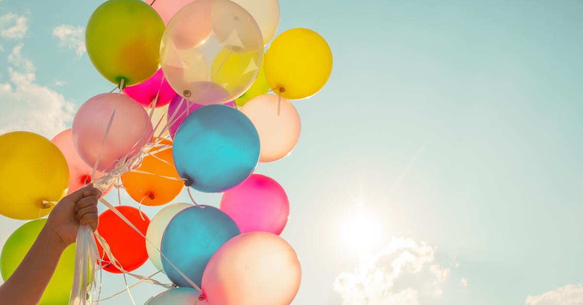 hand holding multi colored balloons