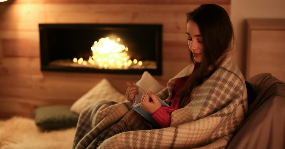 woman reading book near decorative fireplace