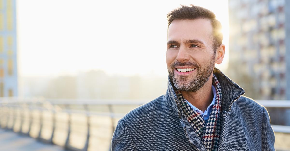 happy man standing outdoors during sunny winter day