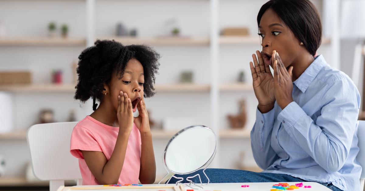 female speech-language pathologist exercising with little girl