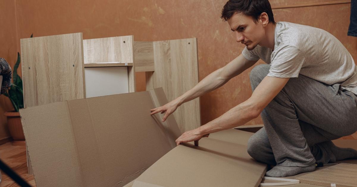 man opening carton box with new furniture for assembly process in flat