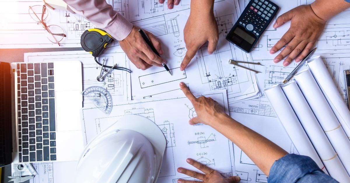 engineers pointing to building on blueprint