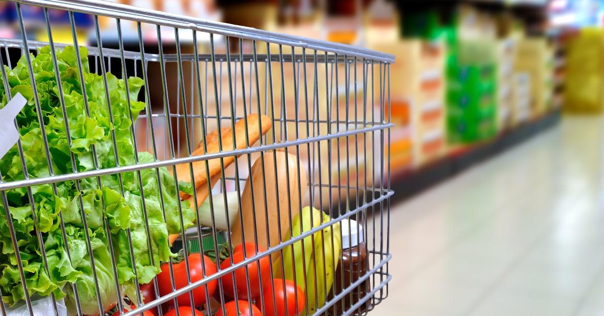 shopping cart full of food in supermarket aisle
