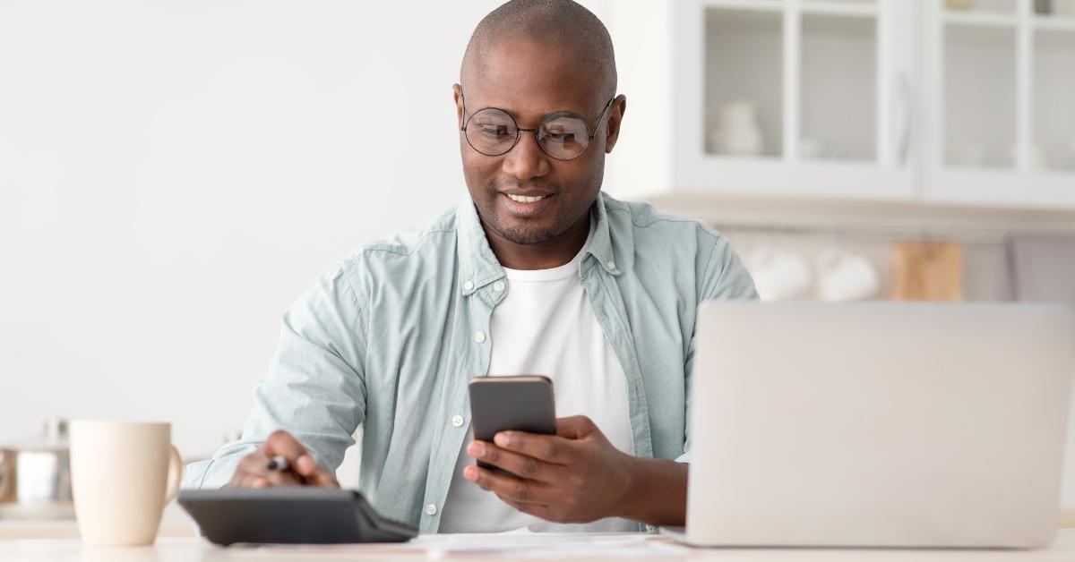 man using calculator phone and laptop 