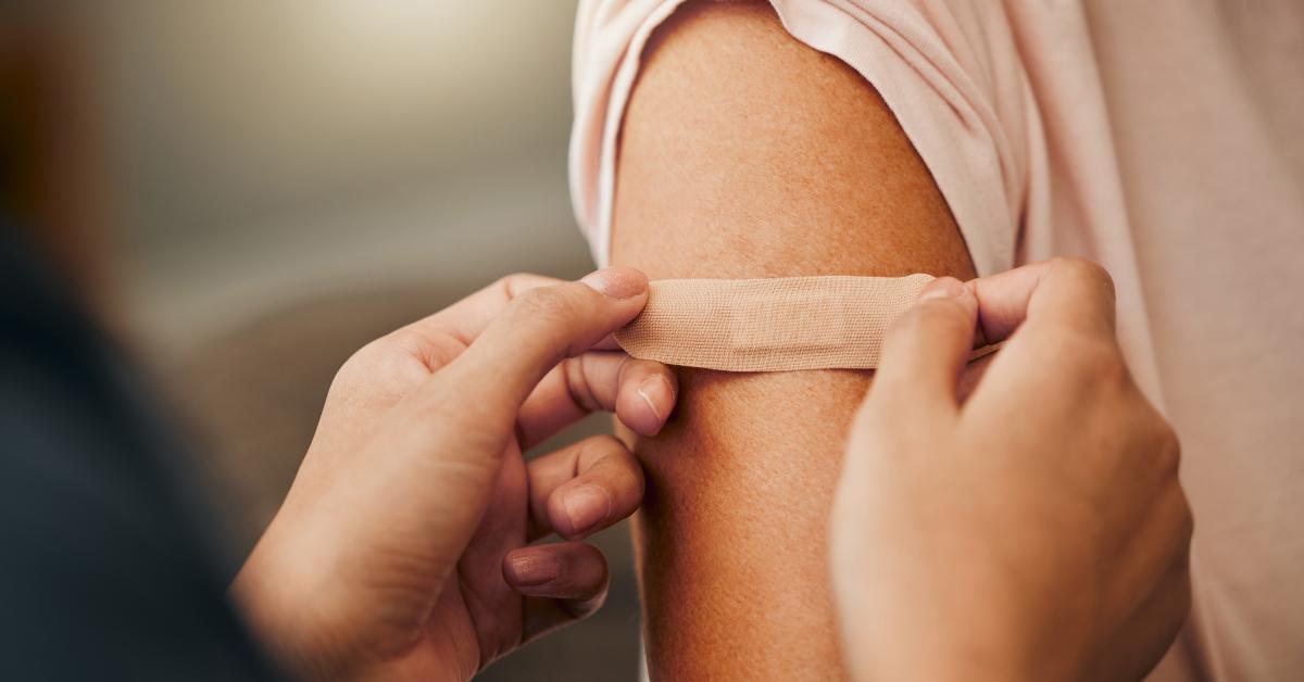 health professional using a bandaid on an arm after medication