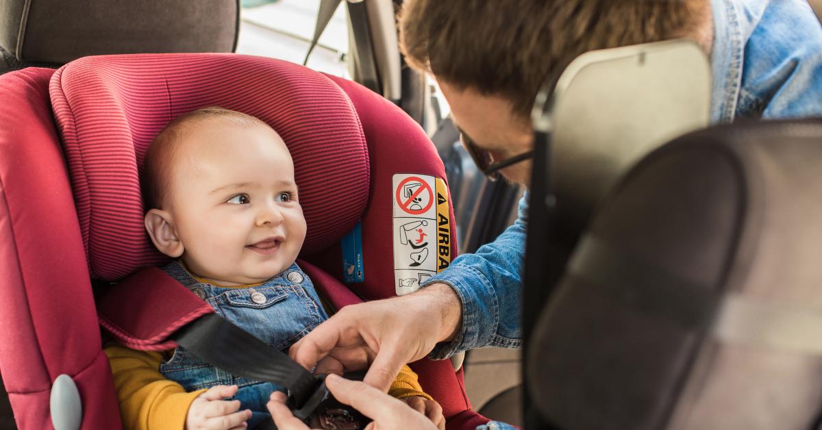 father fasten his baby in car seat
