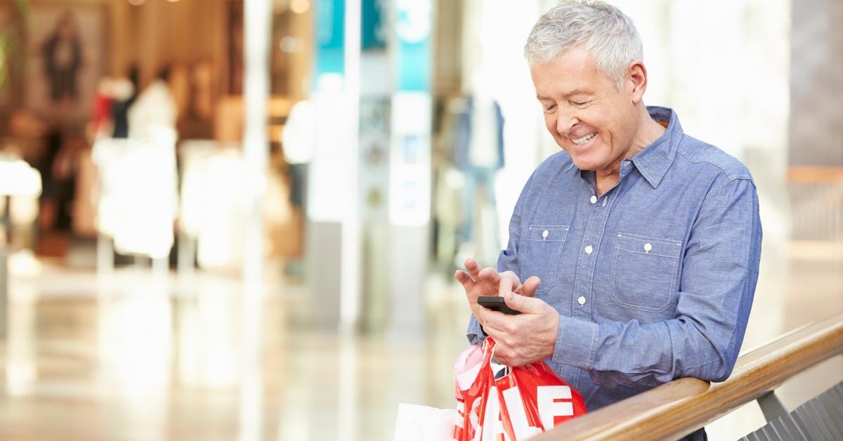 senior man in shopping mall using mobile phone