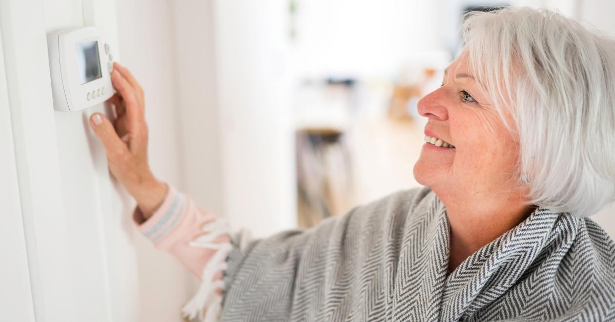 senior woman adjusting her thermostat at home