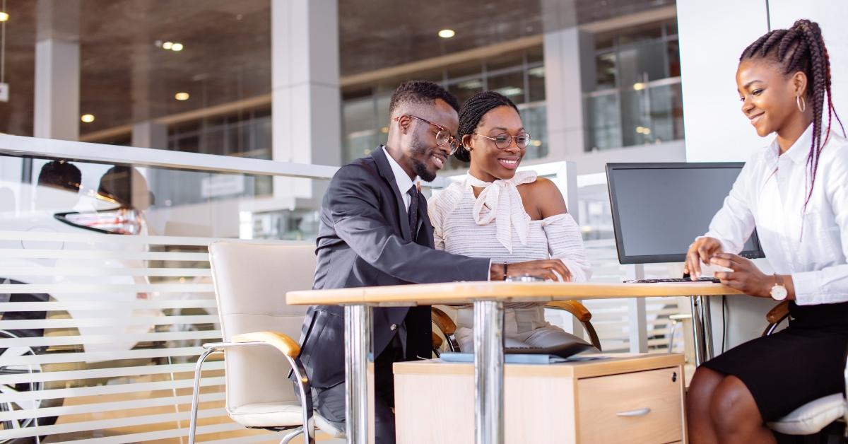 couple signs documents at dealership showroom