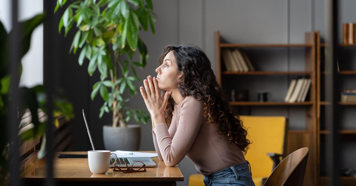 unmotivated female worker sits at office desk with laptop