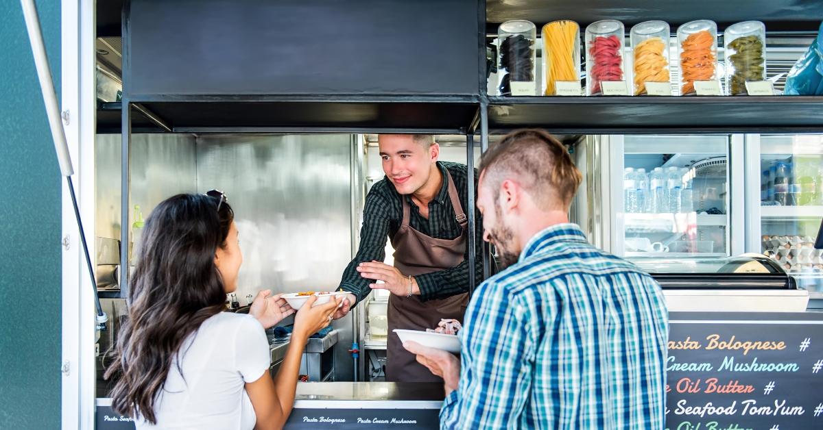 couple buying pasta from food truck at outdoor market