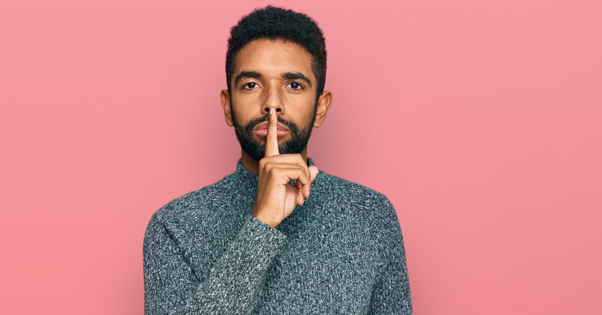 man wearing casual clothes asking to be quiet with finger on lips