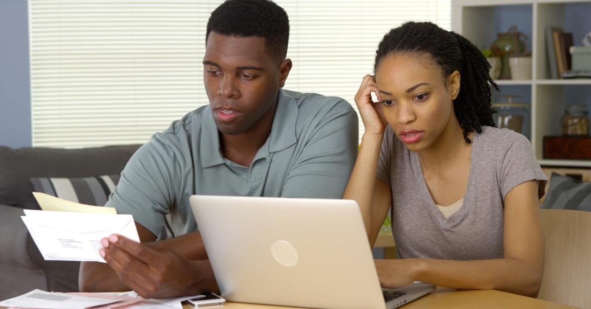 frustrated couple going over bills and finances online