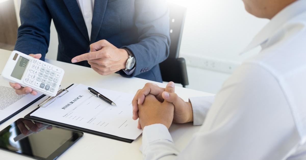 salesman holding a key and calculating a price at the dealership office