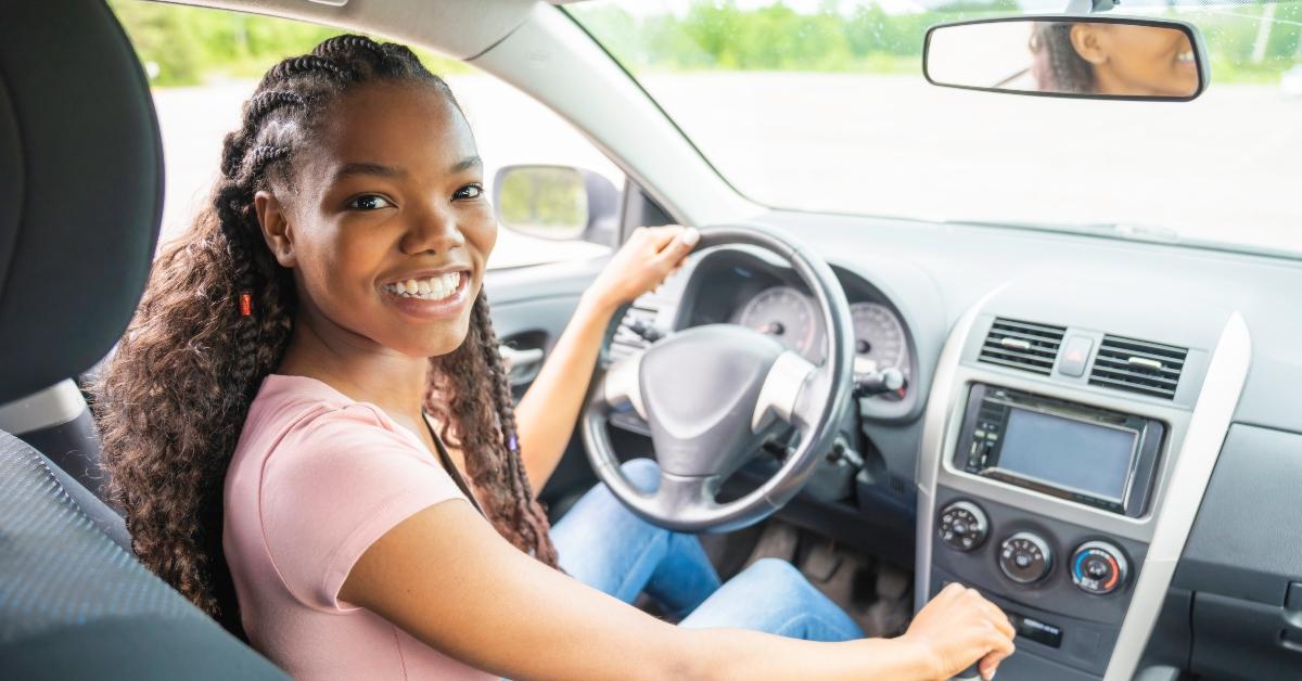 young black teenage driver seated in her new car