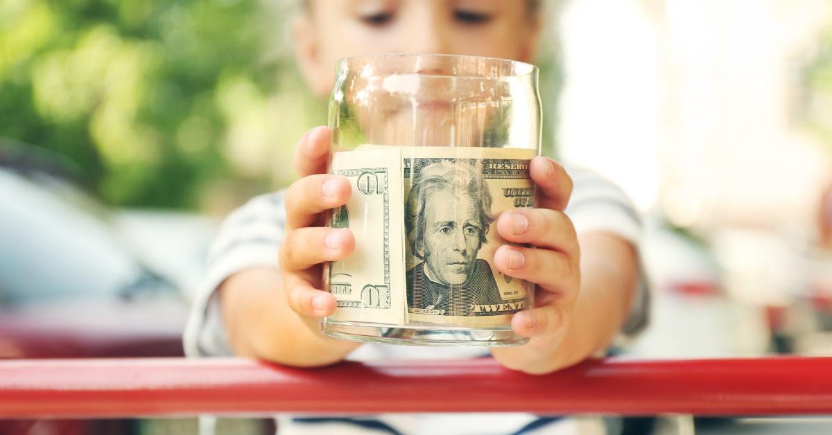 girl holding glass jar with money in hands