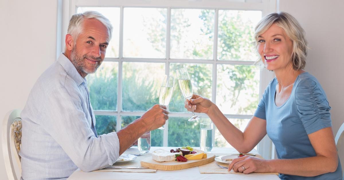 side view portrait of a mature couple toasting drinks over food