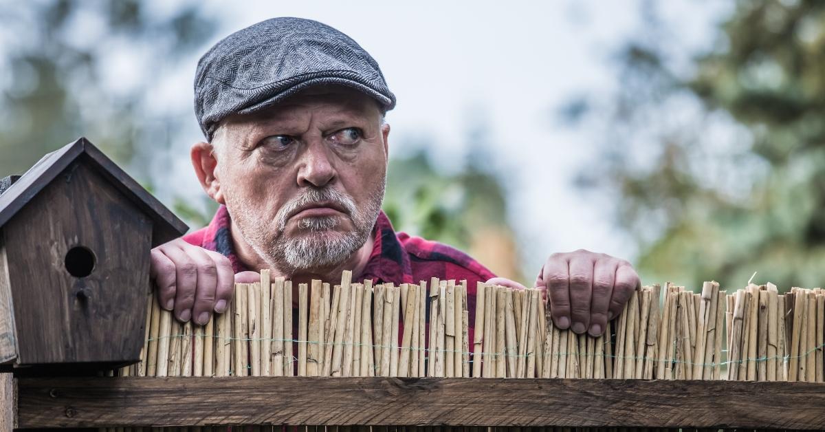 aggressive man watches his neighborhood over the garden fence