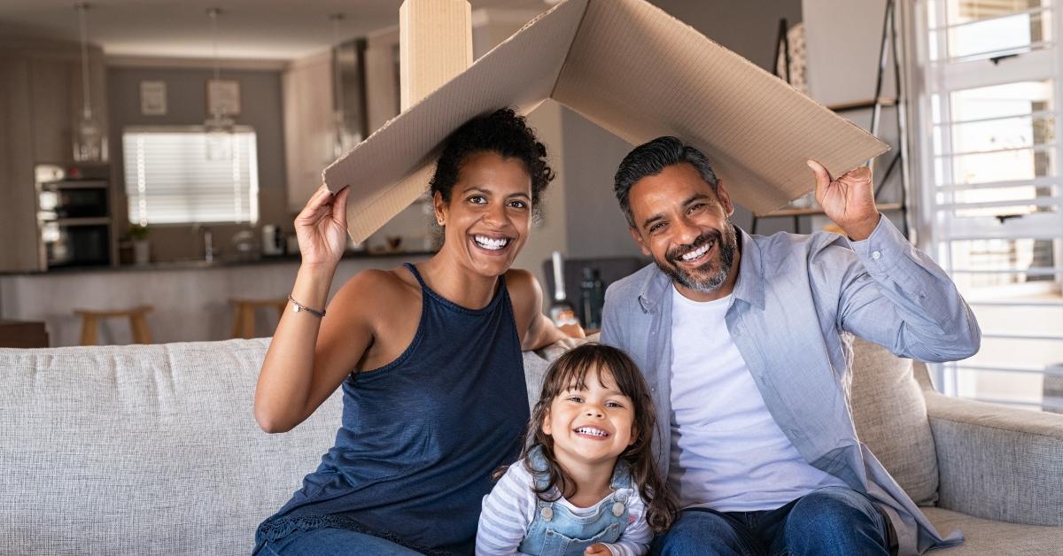 happy multiethnic family with child holding cardboard roof