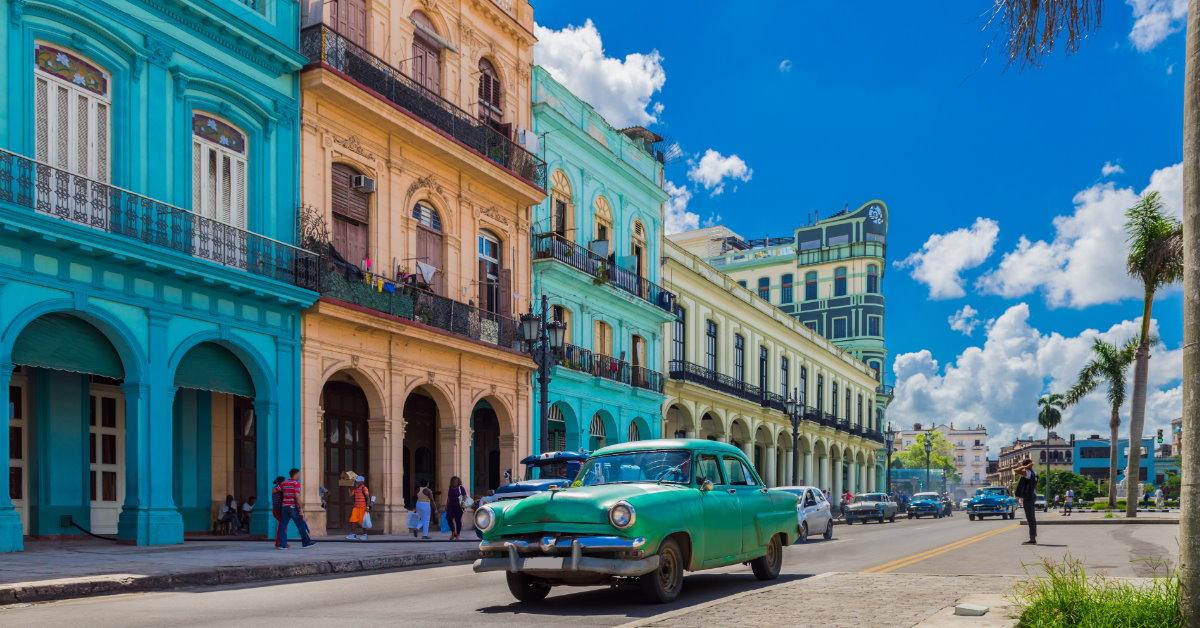 vintage car on street in havana besides colorful building during day time