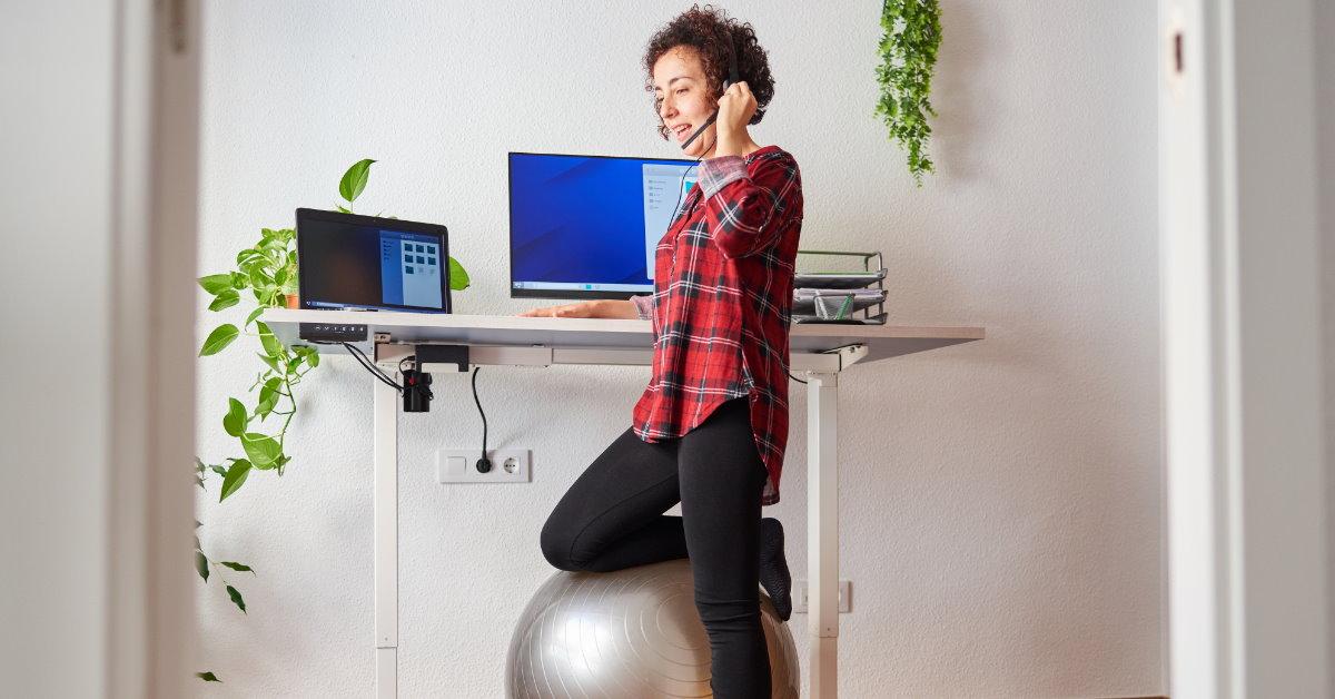woman telecommuting while balancing on a gym ball