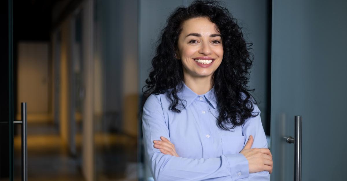 businesswoman smiling inside office with crossed arms