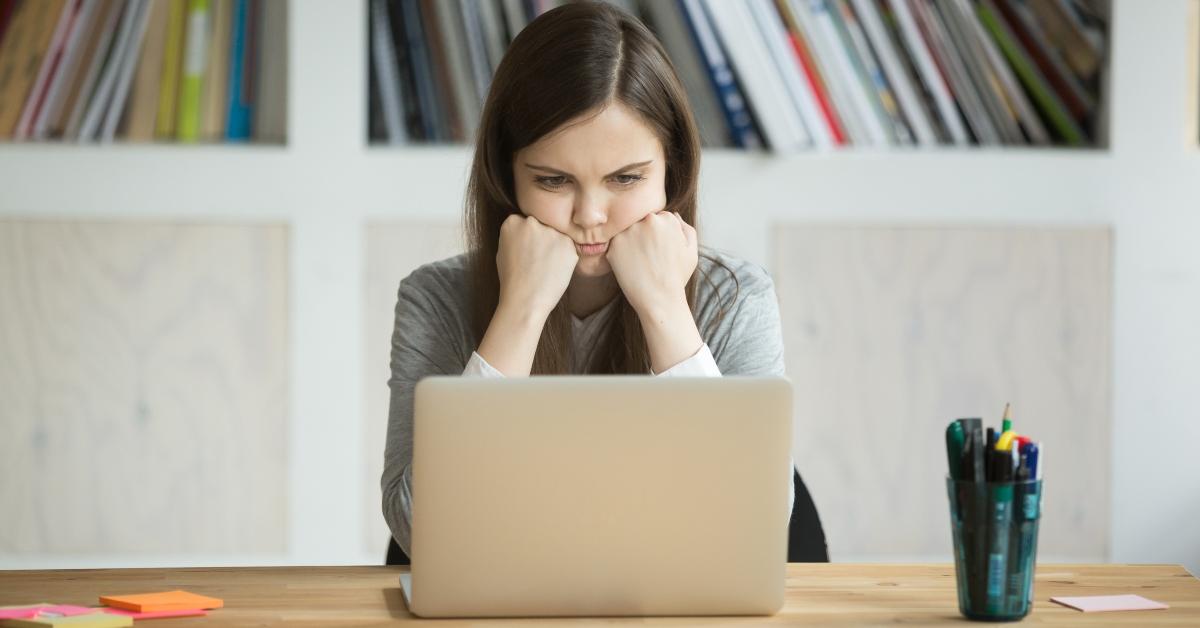 grumpy female office worker looking at laptop screen