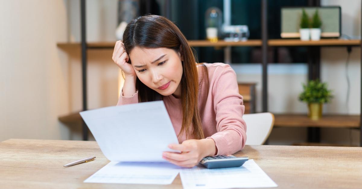 frustrated Asian woman looking at the paper bills