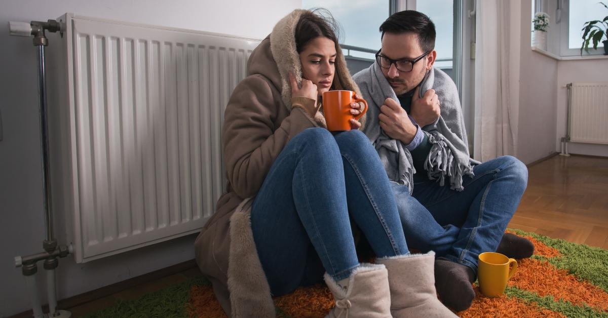 couple sitting beside radiator and freezing