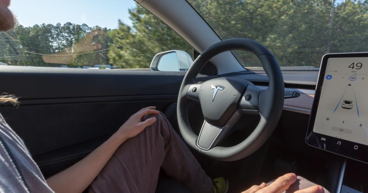 man driving a Tesla Model 3 on autopilot 