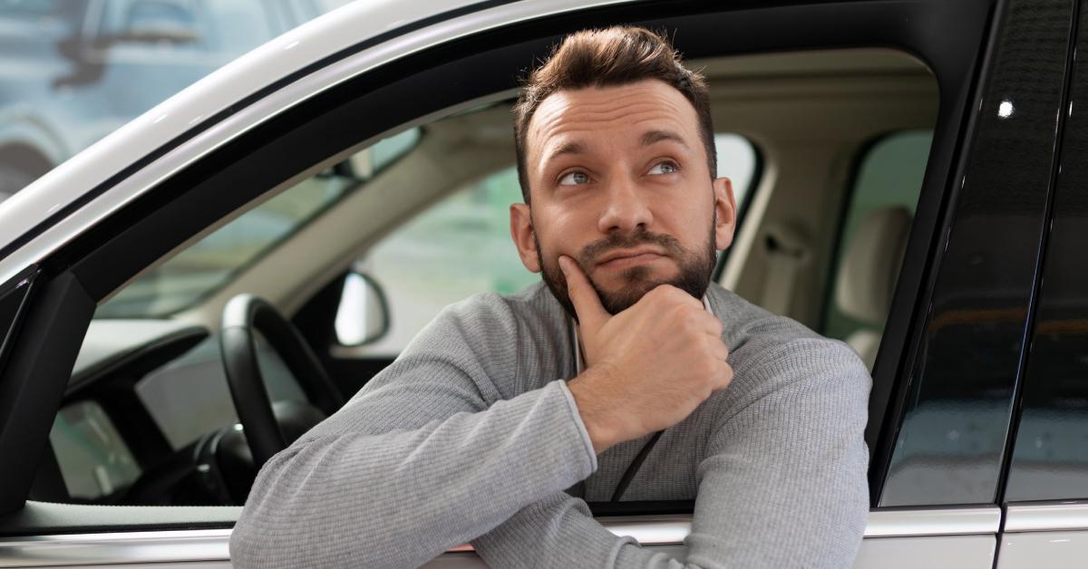 man sits inside a car thinking about buying on credit