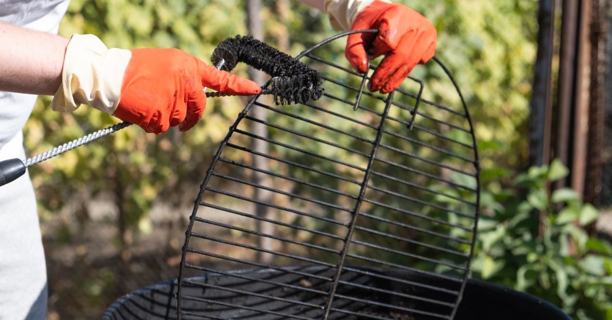 male hand with red gloves cleans round grill