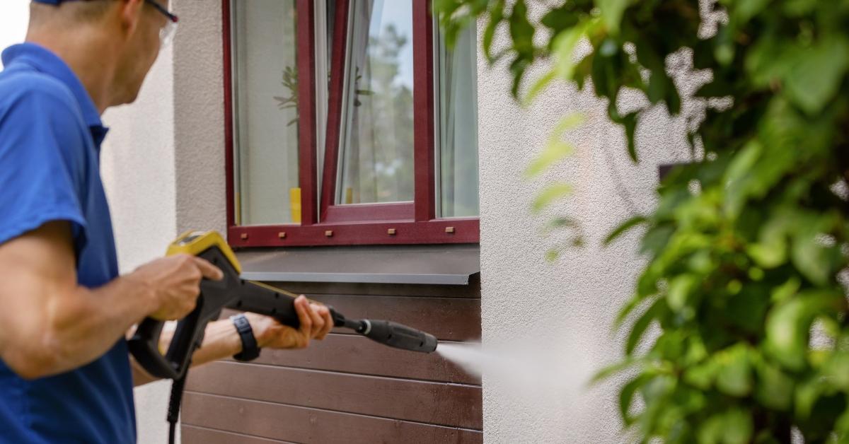 man washing wall with high pressure washer